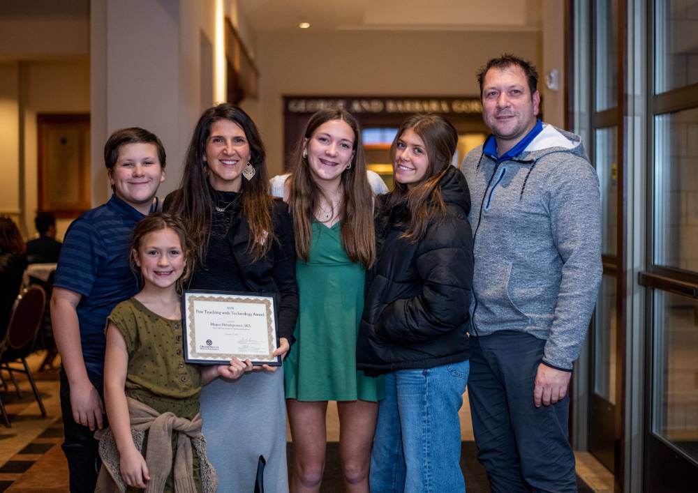 A faculty member's family smiles with them and their award